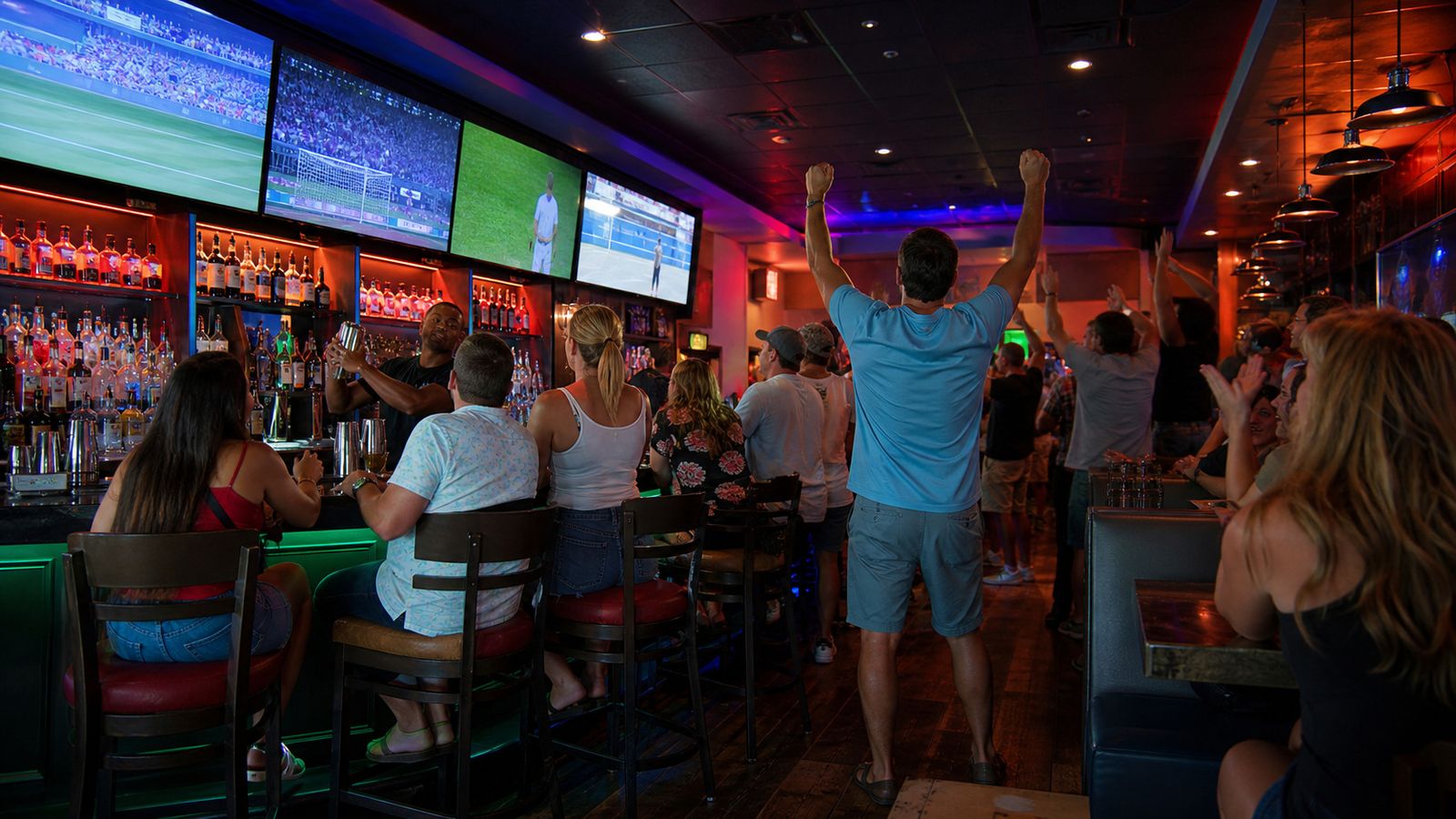 Lively sports bar interior with large TV screens and crowd cheering at live games