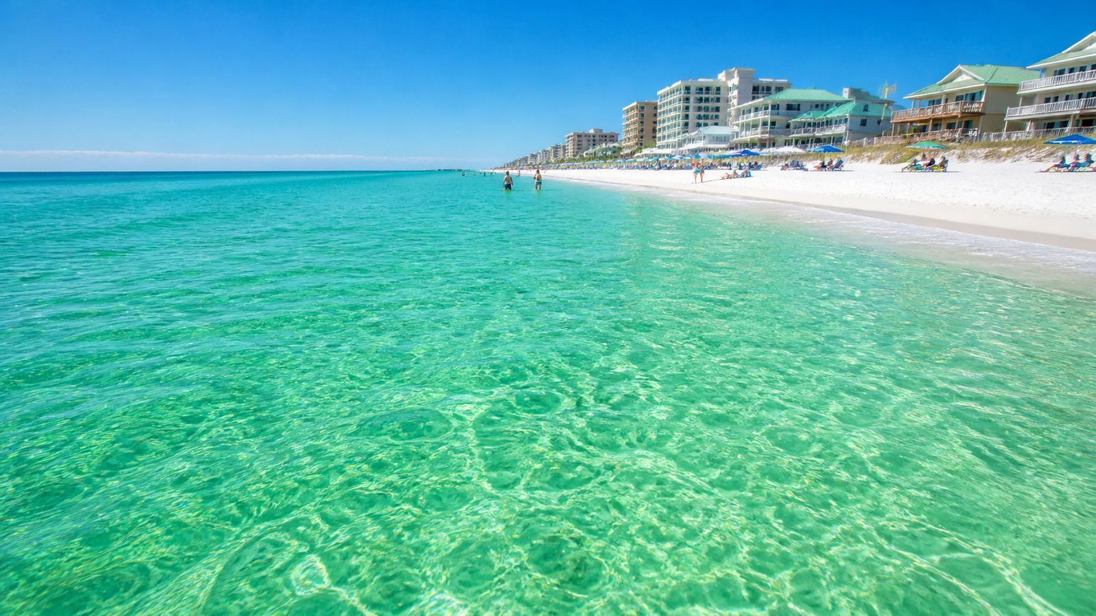 Crystal clear emerald green Gulf water at the Florida Panhandle shoreline showing the quartz sand bottom through shallow water