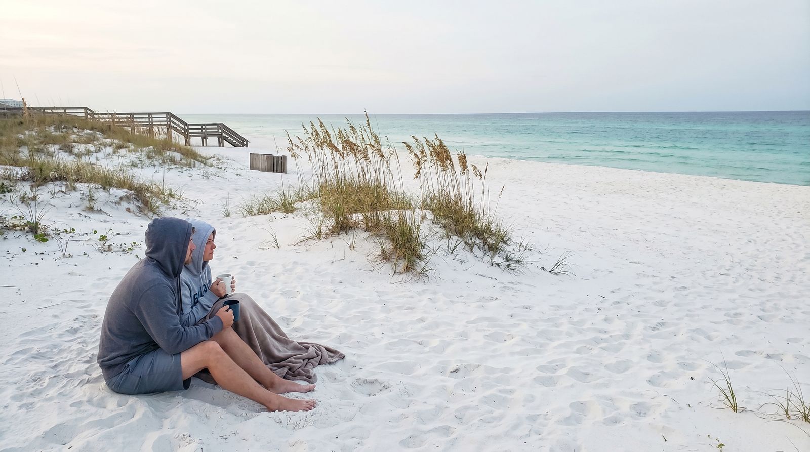 Two empty beach chairs on a pristine white sand beach at Henderson Beach State Park Destin Florida with emerald green Gulf water in the background at soft morning light