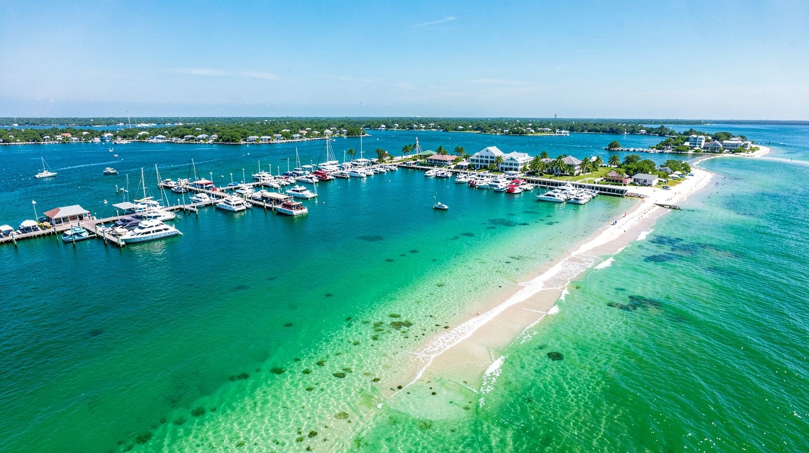 Aerial view of Destin Florida showing the harbor with charter boats alongside the emerald Gulf beach