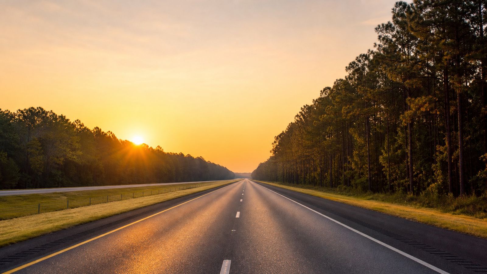 Empty I-59 highway through Alabama at sunrise with orange light on the asphalt, no traffic in sight, ideal early morning road trip departure