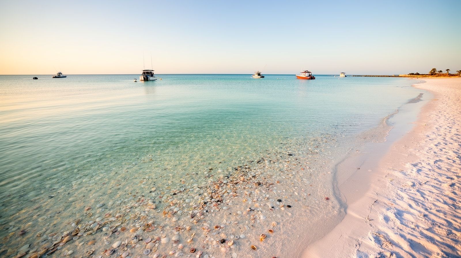 Early morning at Crab Island Destin Florida with just a few boats in perfectly clear turquoise water and golden light before the crowds arrive